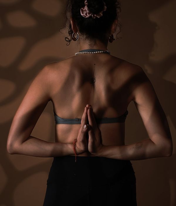 Woman in a calm, flowing yoga pose in a dark studio with soft light.